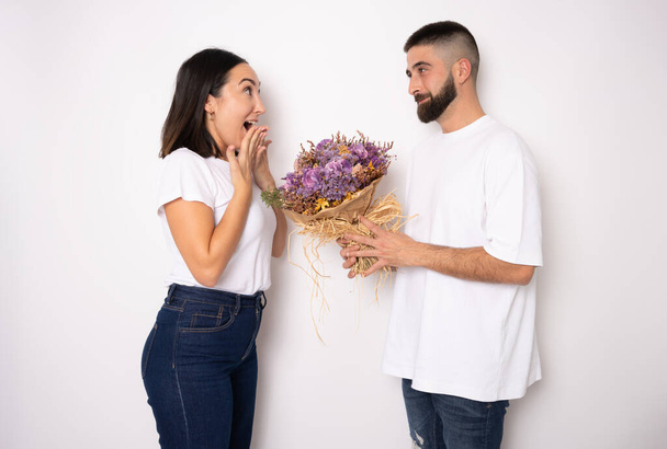 přítel dává květiny na jeho překvapený přítelkyni izolovaných na bílém pozadí - Fotografie, Obrázek