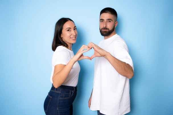 Onnellinen rakastava pari tekee sydämen sormilla eristetty sinisellä pohjalla - Valokuva, kuva