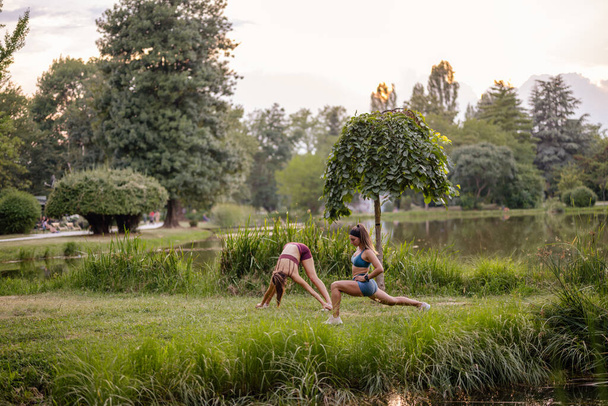 Підійдуть дівчата зігрівають свої тіла і розтягуються в зеленому парку, готуючись до активного відпочинку. - Фото, зображення