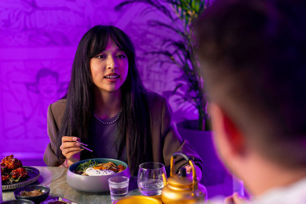 デートでボーイフレンドとレストランで箸で伝統的な韓国料理を楽しんでいる少女の肖像画 - 写真・画像