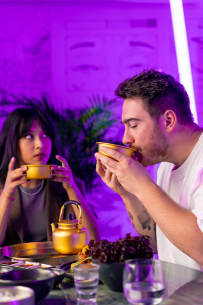 влюбленная пара за столом обедает в корейском ресторане, пьет традиционный напиток маколи - Фото, изображение
