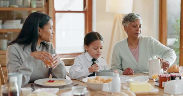 Perheaamiainen äidin, tyttären ja isoäidin kanssa syömässä ruokaa yhdessä kotona aamulla. Lapset, rakkaus tai hauska nuori nainen, lapsi ja vanhempi olohuoneessa, liimaus aterian aikana. - Materiaali, video