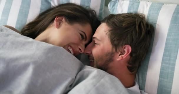 Couple, together and laugh while lying in bed for sleep, relaxing or home. Happy man, woman and love in bond for dating, marriage and relationship for bonding, care or rest for comfort on weekend. - Footage, Video
