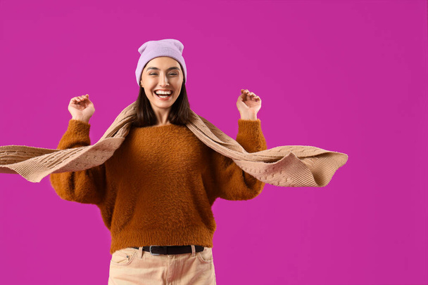 Νεαρή γυναίκα με χειμωνιάτικα ρούχα σε μωβ φόντο - Φωτογραφία, εικόνα