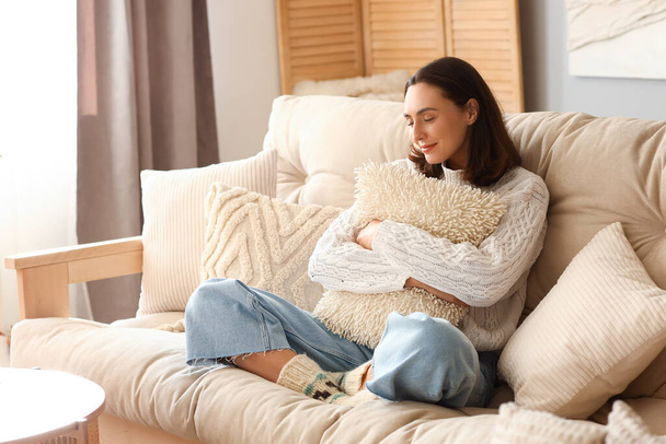 Junge Frau mit Kopfkissen sitzt zu Hause auf Sofa - Foto, Bild