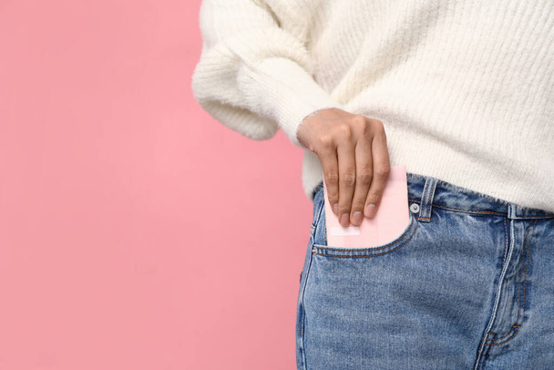 Mooie jonge vrouw met menstruatie pad op roze achtergrond, close-up - Foto, afbeelding