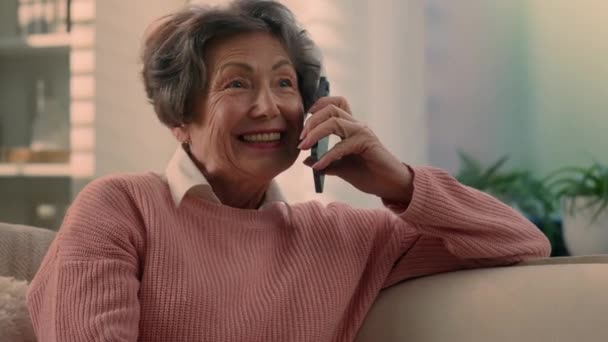 Szczęśliwy biały stary kobieta beztroski w średnim wieku senior lady wesoły uśmiechnięty emeryt babcia starsza kobieta babcia mówi przez smartfon telefon komórkowy rozmowa dzielenie się nowinkami na telefon komórkowy w domu - Materiał filmowy, wideo