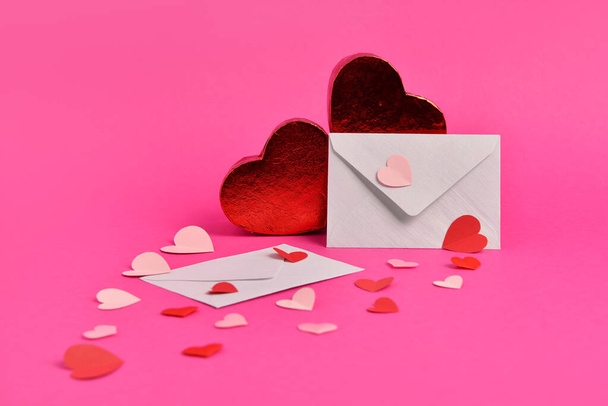 Σύνθεση με διαφορετικές χάρτινες καρδιές και φακέλους σε ροζ φόντο - Φωτογραφία, εικόνα