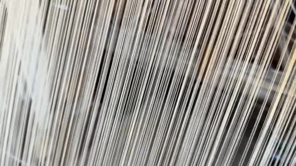 Průmyslová textilní továrna. Detailní záběr silných bílých nití pohybujících se tkalcovským stavem, žena, která vyrábí na tradičním stavu - Záběry, video