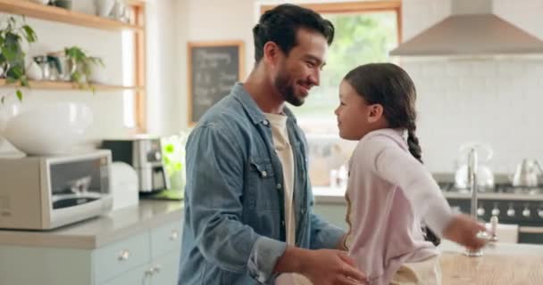 Perhe, isä ja tytär halaavat keittiössä rakkautta, luottamusta tai sitoutumista yhdessä kodissaan. Lapset, hymyilkää ja turvatkaa onnellisen nuoren miehen kanssa, joka syleilee suloista tyttölastaan heidän talossaan.. - Materiaali, video