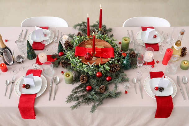 Feestelijke tafelopstelling met kerstversiering en brandende kaarsen in de keuken - Foto, afbeelding