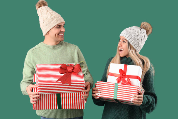 Glückliches junges Paar mit Weihnachtsgeschenken auf grünem Hintergrund - Foto, Bild