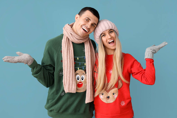 Νεαρό ζευγάρι σε χριστουγεννιάτικα πουλόβερ σε μπλε φόντο - Φωτογραφία, εικόνα