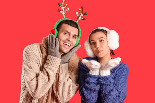 Happy young couple in winter clothes on red background - Photo, Image