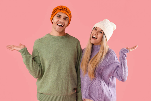 Boldog fiatal pár téli ruhák rózsaszín háttér - Fotó, kép