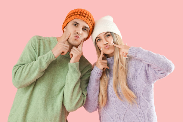 Joyeux jeune couple en vêtements d'hiver sur fond rose - Photo, image