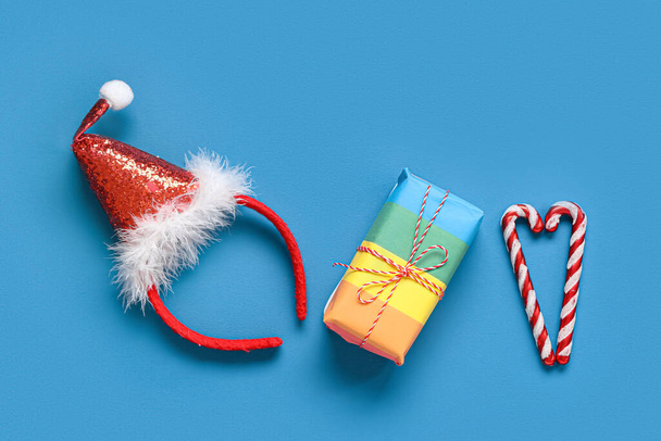 Chapeau de Père Noël avec boîte cadeau coloré et cannes de bonbons sur fond bleu. Concept LGBT - Photo, image