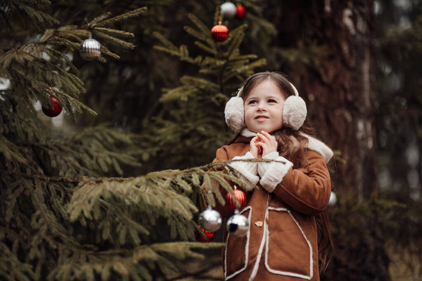 アクティブな少女は,子供の頃にボールを飾るXmasツリーを楽しんで森で休んでいます. クリスマスと新年の冬の休暇シーズンの屋外を祝う女性の子供 - 写真・画像