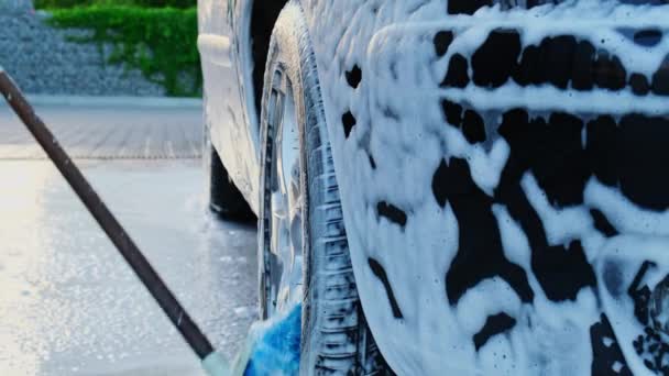 Das Waschen eines schwarzen Luxusautos auf einer berührungslosen Waschstraße. Reinigung der Details des Autos. Waschmaschine mit Selbstbedienungsschaum und Hochdruckwasser. Sauberkeit und Ordnung im städtischen Umfeld - Filmmaterial, Video