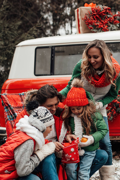 Ευτυχισμένη οικογένεια γιορτάζει Χριστούγεννα και Πρωτοχρονιά χειμερινές διακοπές σεζόν εξωτερική. Ενεργά παιδιά με τους γονείς χαρούμενους περνώντας χρόνο μαζί αγκαλιάζει διασκεδάζοντας κοντά Χριστούγεννα λεωφορείο χαίρεται με το πρώτο χιόνι - Φωτογραφία, εικόνα