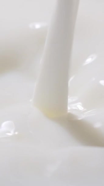 Powolny ruch wylewania mleka. Pionowe wideo. - Materiał filmowy, wideo