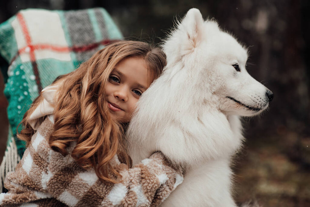 Kobieta dziecko świętuje Boże Narodzenie i Nowy Rok sezon zimowy na świeżym powietrzu. Mała dziewczynka radosne spędzanie czasu na świeżym powietrzu z białym Samoyed pies w pobliżu autobusu Bożego Narodzenia korzystających z dzieciństwa - Zdjęcie, obraz