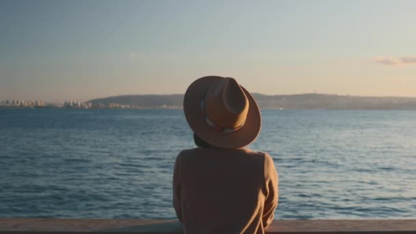Žena pluje na výletní lodi, dívka stojí u plotu na lodi a dívá se na moře, cestuje trajektem, bruneta v kabátě a klobouku obdivuje oceán. Cestování a dobrodružství. - Záběry, video