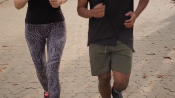 移動ショット 秋の市立公園で一緒に走っている2人の若いアスリート幸せな笑うアラビア人男性とコーカサス女性は,カップルジョギング朝の活動ジョギングを愛し,健康的なライフスタイルスポーツトレーニング屋外を実行します - 映像、動画