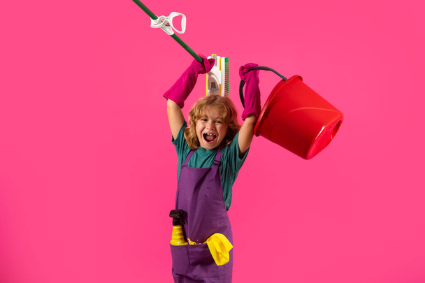 Kleines Kind putzt zu Hause. Kind macht Hausarbeit und hat Spaß. Studio isoalted Porträt der Haushälterin mit nassem Flachmopp auf rosa Hintergrund - Foto, Bild