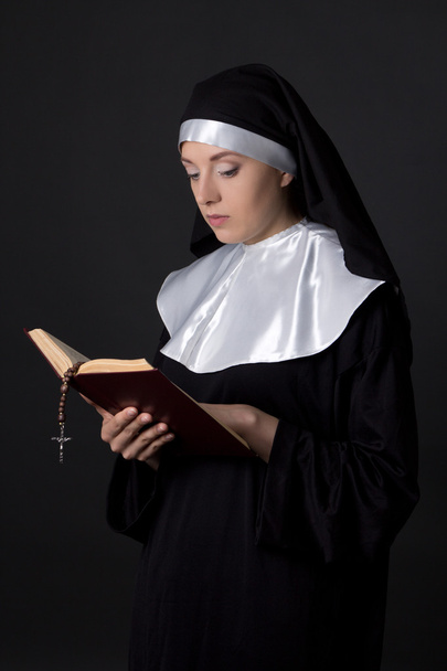 young beautiful woman nun reading bible over grey - Foto, afbeelding