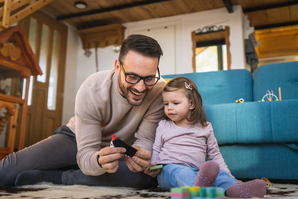 Father and daughter on the floor at home mature adult caucasian man play with finger puppets with his two years old child toddler girl having fun parenting and bonding family time concept copy space - Photo, Image