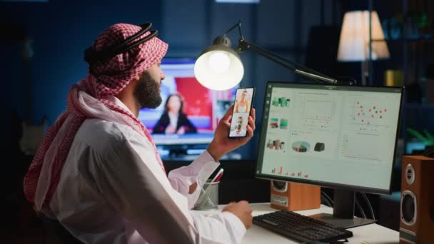 Мусульманський телефонний працівник та співробітники у статистичних наборах даних для перевірки викликів у малопомітно освітленому офісі. Арабський працівник, що оптимізує ключові показники продуктивності з колегами у відеоколективі - Кадри, відео