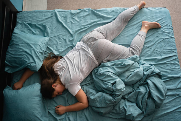 Uyumak için rahat bir poz. Genç bir kadının uyuduğunu, yatakta yüzüstü yattığını. Boşluğu kopyala - Fotoğraf, Görsel