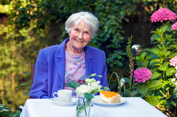 Donna anziana seduta in giardino
 - Foto, immagini