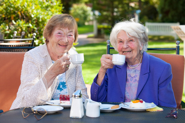 Старші жінки розслабляються за садовим столом
 - Фото, зображення