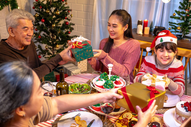 Щасливі люди святкують на столі, коли Різдво і Новий рік вдома. Веселий літній чоловік, дочка і дитина їдять вечерю їжу з веселим різдвяним прикрасою, коли щасливе новорічне свято. - Фото, зображення