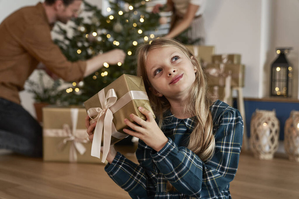 Caucasian girl holding a Christmas present and what is in - Photo, Image