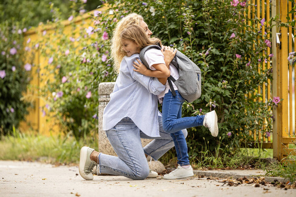 Madre e figlia abbracciano e si baciano prima di andare a scuola. Amore tra genitore e figlio. - Foto, immagini