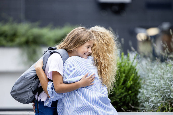 Mãe e filha abraçando e beijando antes de sair para a escola. Amor entre pais e filhos. - Foto, Imagem