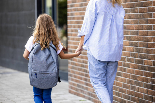 Mãe e filha de mãos dadas como caminhando em direção à escola. - Foto, Imagem