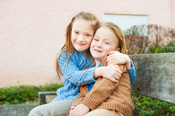 Deux mignons enfants assis sur un banc, grande soeur étreignant petit frère
 - Photo, image