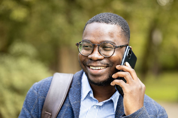 Закрыть вид афроамериканца, улыбающегося и разговаривающего по телефону. - Фото, изображение