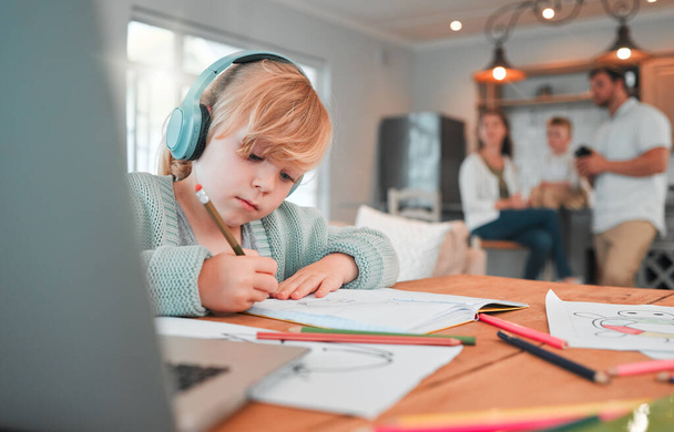 Child, headphones and drawing in kitchen at laptop in home for online class, distance studying or virtual learning help. Kid, music and study information or writing, reading or development at table. - Photo, Image