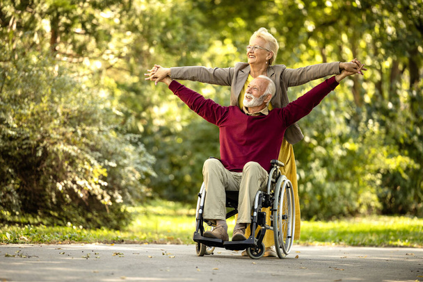 Позитивні літні люди в інвалідному кріслі зі зброєю підняли почуття щасливого і жвавого. Страхування життя та здоров'я. - Фото, зображення