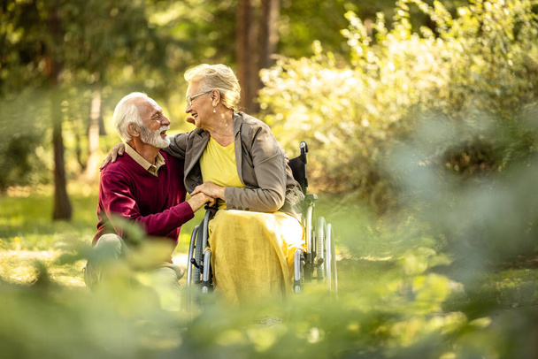 Старший чоловік і літня леді в інвалідному візку показують любов і повагу один до одного. - Фото, зображення