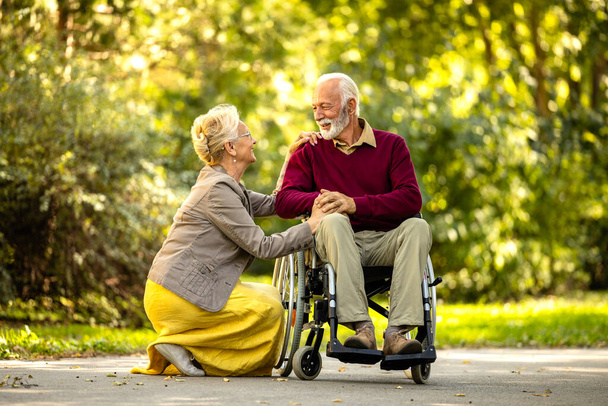 Старша жінка проводить час зі своїм чоловіком у інвалідному кріслі. Насолоджуючись пенсією разом. - Фото, зображення