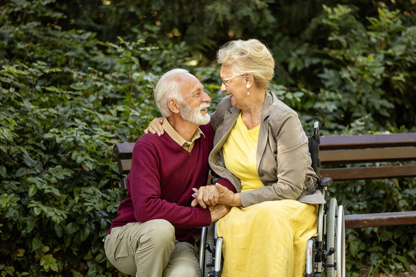 Älterer Mann kümmert sich um ältere Frau im Rollstuhl und zeigt Liebe und Respekt. - Foto, Bild