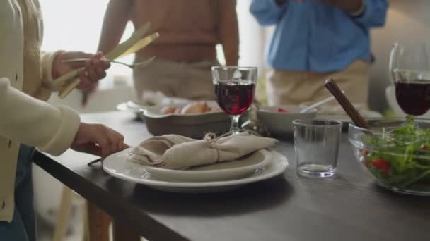 Primer plano de niña afroamericana poniendo tenedor y cuchillo por platos mientras se establece la mesa para la celebración de las vacaciones con la familia - Imágenes, Vídeo