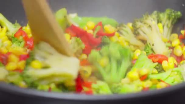 Cocinar una fritura colorida con verduras frescas y una cuchara de madera - Metraje, vídeo