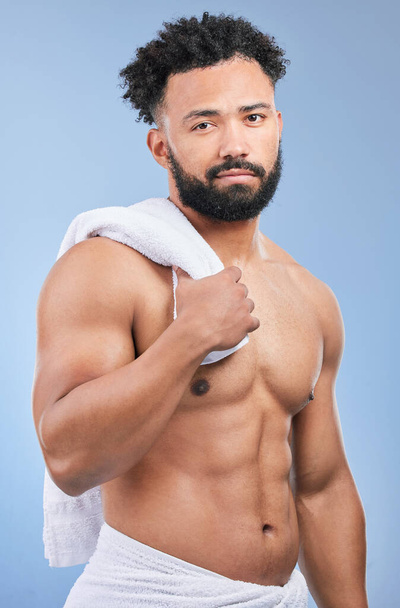 Shower towel, studio portrait and man confident in morning routine, body cleaning or self care maintenance. Bathroom skincare, grooming wash and model hygiene, beauty and dry skin on blue background. - Photo, Image